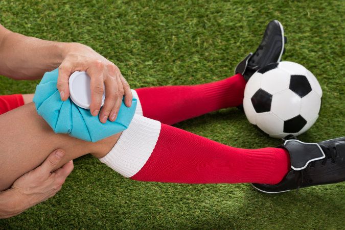 Image of soccer player applying ice to knee to illustrate physical therapy