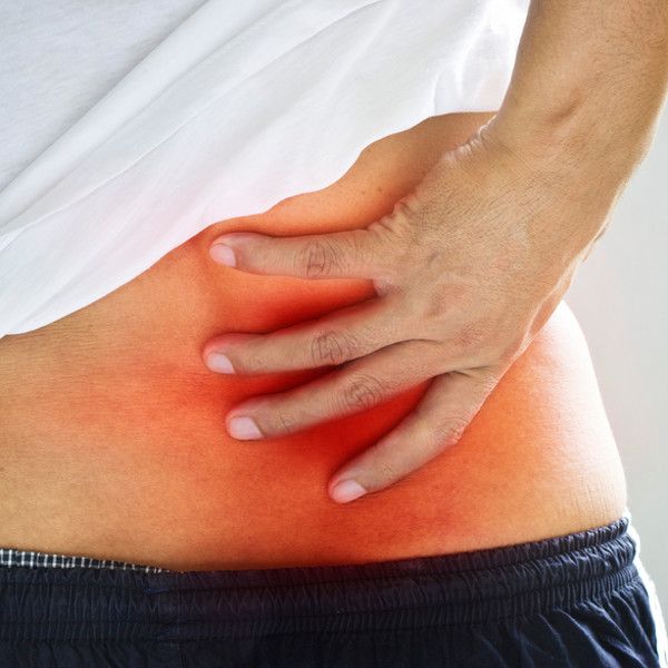 Picture of a man holding a red spot indicating pain in the low back.