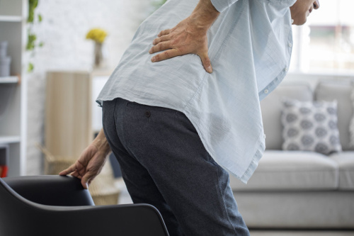 Photo of a man grasping his back due to low back pain.