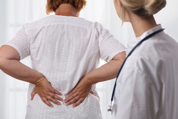 A woman with lower back pain is examined by a chiropractor for a herniated disc treatment.