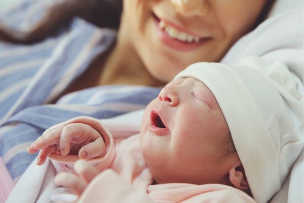 Woman smiles next to her newborn baby