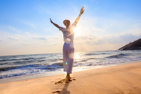 Woman raises her arms on the beach
