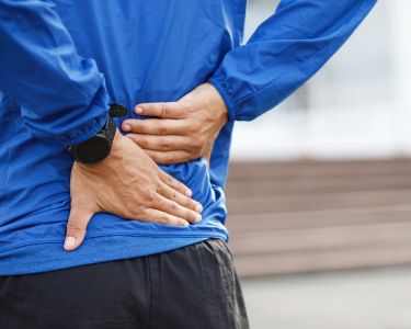 Close up of a person holding their lower back