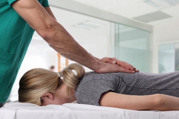 A chiropractor treats back pain in a female patient