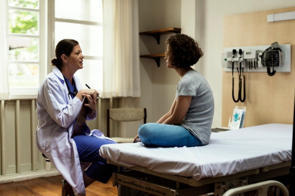 An image showing a teenager receiving a medical examination for their sports physical. 