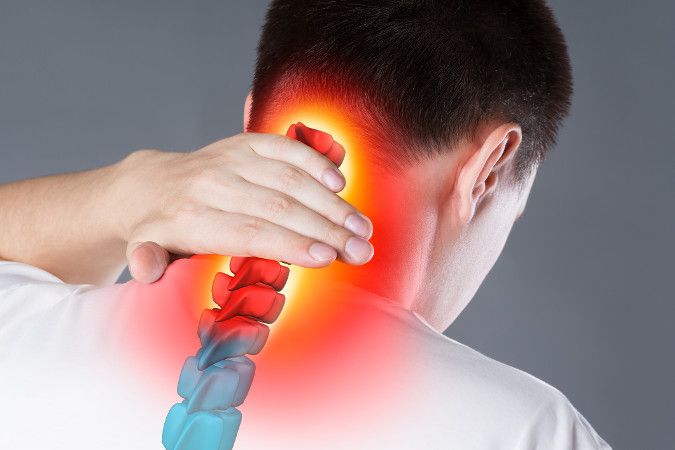 An image showing a man holding the back of his neck. A graphic of a spine with pain targeted in red is over the man’s backside and neck. 