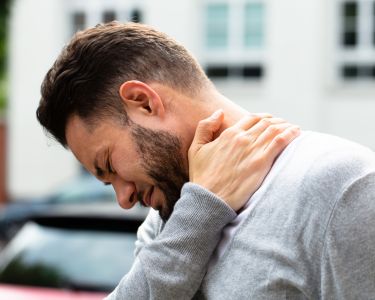 Man in need of a chiropractor holds his neck