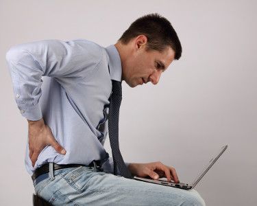 A man holds his back in pain from sciatic nerves