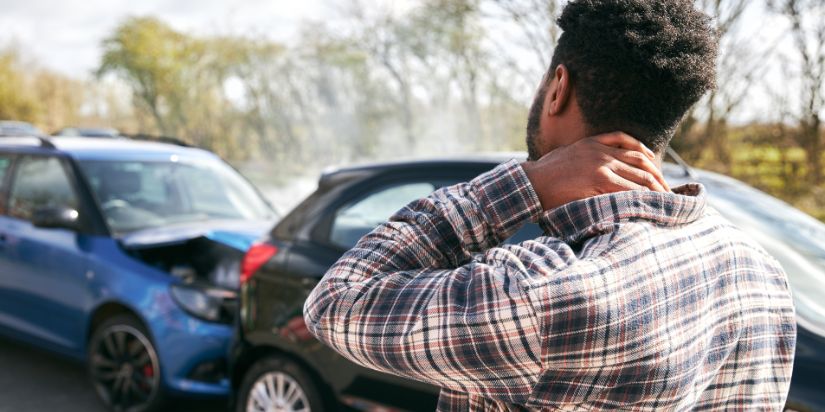 A man holds his neck in pain after a car accident