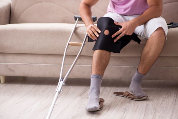 Man sitting on a couch holding a hurt leg