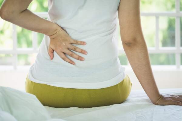 Woman in pain holds hand to her back