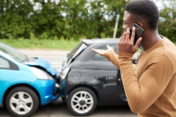 A man makes a phone call at the scene of a car crash