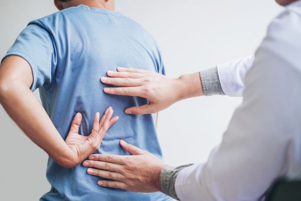 Doctor helps diagnose pain by gently pressing on patient’s back