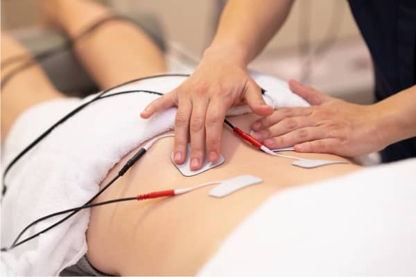 Electrical muscle stimulation being set up on a patient’s back, one of the chiropractic services we perform