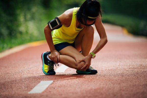 A runner needing sports medicine grabs her leg in pain