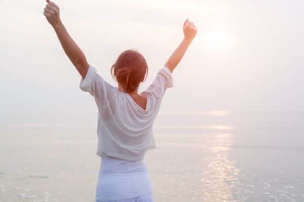 Woman excitedly greets day with arms up