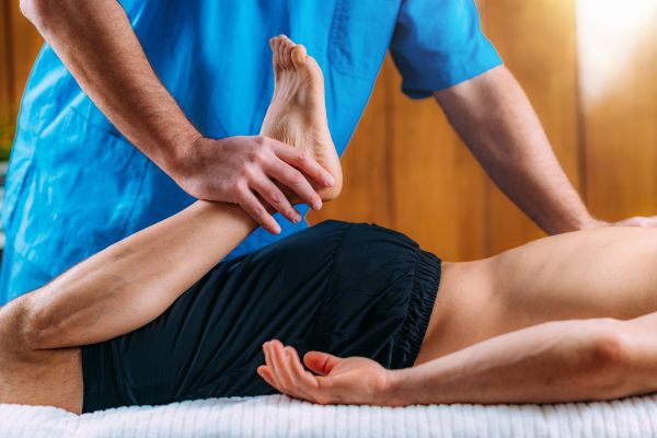 A physical therapy doctor stretches a patient’s leg