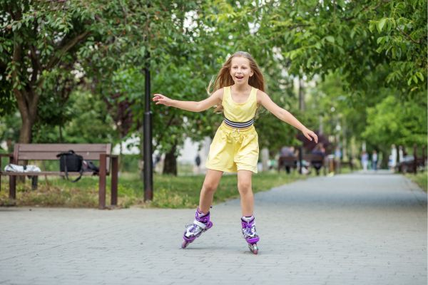 Child rollerblades in a park