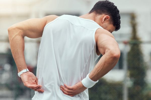 Athlete holding his back in pain, needing sports medicine chiropractic services